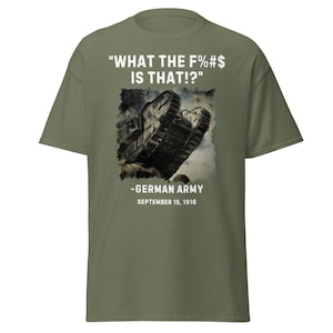 May include: Olive green t-shirt with a graphic of a tank and the text "WHAT THE F%#$ IS THAT!?" and "-GERMAN ARMY SEPTEMBER 15, 1916" in white. The tank graphic is in black and gray.