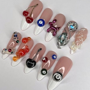 May include: Ten long, almond-shaped, white-tipped nails with various colorful 3D nail art designs.  The designs include cherries, a pool ball, a balloon animal, a crystal, a feather, and colorful bubbles.