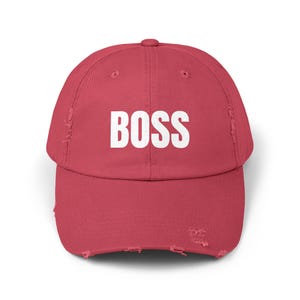 May include: A red distressed baseball cap with the word "BOSS" in white lettering.