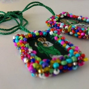 May include: Two rectangular pendants with colorful beaded frames and green cords. The pendants feature religious imagery. The beads are in various colors, including red, blue, yellow, and green. The cords are a bright green color.