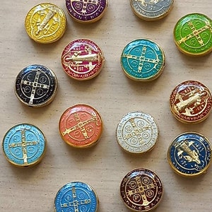 Puede incluir: Una colecci&oacute;n de 14 medallones redondos con borde dorado y dise&ntilde;os de esmalte de varios colores. Cada medall&oacute;n presenta una cruz con diferentes s&iacute;mbolos y texto, incluyendo las palabras "S-M-V-R-S-N-S" y "P-L-U-B-N-R-D-S".