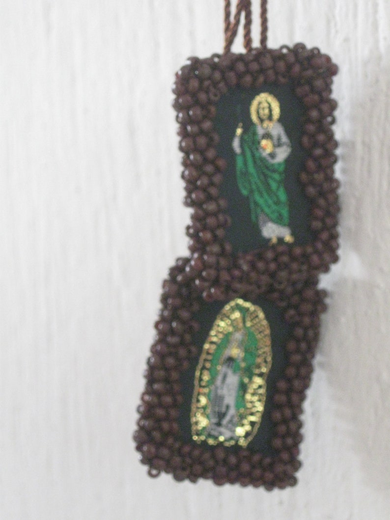 May include: Two small framed images with religious figures. The frames are made of brown beads and the images are of Jesus and the Virgin Mary.