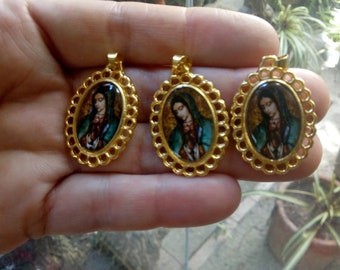 Puede incluir: Tres colgantes de color dorado con un diseño filigranado detallado. Cada colgante presenta una imagen redonda y colorida de la Virgen María.