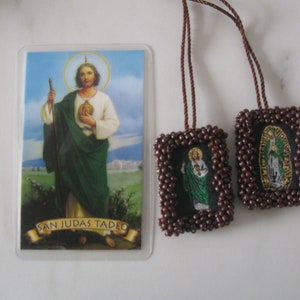 May include: Two brown beaded religious medallions with images of Saint Jude Thaddeus and Our Lady of Guadalupe. The medallions are attached to brown cords. A printed card with an image of Saint Jude Thaddeus and the text "San Judas Tadeo" is also shown.