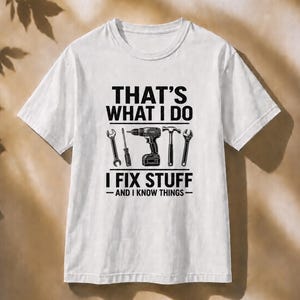 May include: A white short-sleeve t-shirt featuring black text that reads THAT'S WHAT I DO I FIX STUFF - AND I KNOW THINGS - with a graphic illustration of a wrench, screwdriver, power drill, hammer, and another wrench centered on the chest.
