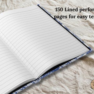 Może przedstawiać: Otwarty notatnik z białymi liniowanymi stronami i niebiesko-białą wzorzystą okładką. Widoczny jest tekst 150 Lined perforated pages for easy tearing. Notatnik posiada czarny grzbiet oraz małe okrągłe logo z napisem La Vie Vibe.