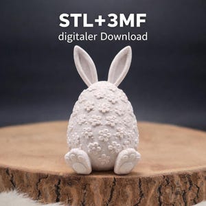 Könnte beinhalten: Ein weißes, hasenförmiges Dekorationsobjekt mit floralem Muster, das auf einer Holzoberfläche sitzt. Der Hase hat lange Ohren und pfotenartige Füße. Der Text "STL+3MF digitaler Download" ist oben zu sehen.