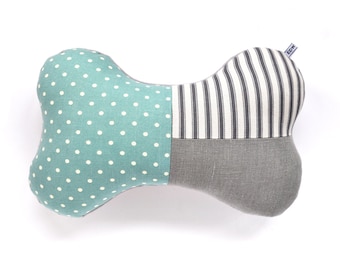 Puede incluir: Una almohada con forma de hueso de perro de color turquesa y gris con lunares blancos y rayas blancas y negras. La almohada tiene una pequeña etiqueta que dice "EDX".