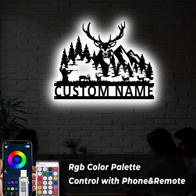 May include: Black metal wall art featuring a deer, trees, mountains, and a hunter silhouette. The text "CUSTOM NAME" is displayed below the scene. The image also shows a phone and remote control with the text "RGB Color Palette Control with Phone&Remote".