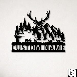 May include: Black metal wall art featuring a deer with large antlers, set against a forest and mountain backdrop. A hunter is depicted aiming a rifle. The text "CUSTOM NAME" is displayed below the scene.