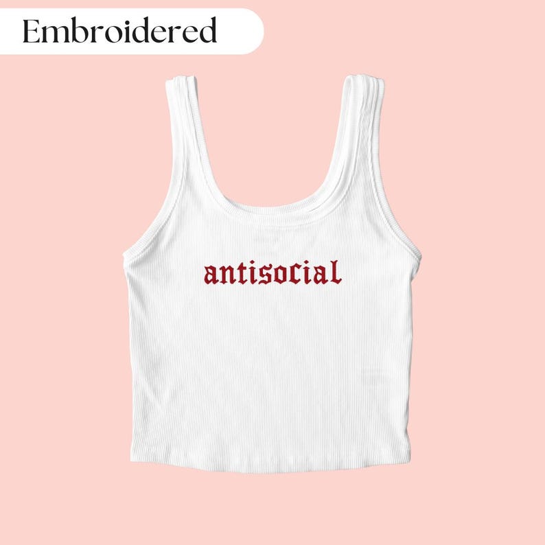Puede incluir: Camiseta sin mangas blanca acanalada con la palabra "antisocial" bordada en letras g&oacute;ticas rojas. La palabra "Embroidered" est&aacute; en un &oacute;valo blanco en la esquina superior izquierda. La camiseta sin mangas est&aacute; sobre un fondo rosa claro.