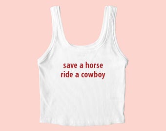 May include: White ribbed tank top with the text "save a horse ride a cowboy" in red. The word "Embroidered" is at the top left corner. The top has a scoop neck and is sleeveless.