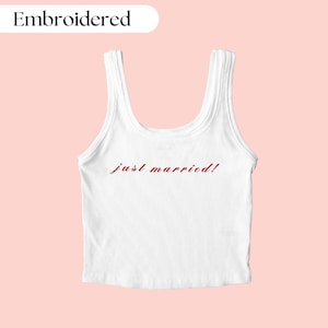 May include: White tank top with the words "just married!" embroidered in red on the front.