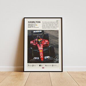 May include: A red and black Formula 1 race car with the number 44 on the side. The car is on a track and the driver is wearing a helmet. The text "HAMILTON" is at the top of the image, along with the quote "As a driver, you've always got to believe in your heart that you've got what it takes to win it. You've always got to believe in yourself. You've always got to arrive on the day and believe it can happen. You've always got to believe in the positives."
