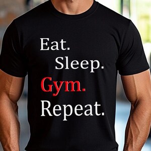 Könnte beinhalten: Ein schwarzes T-Shirt mit weißem Text, der "Eat. Sleep. Gym. Repeat." lautet. Das Wort "Gym" ist rot.