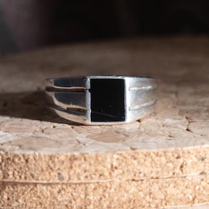 Peut inclure: Une tasse en céramique blanche avec une anse noire et le texte "But First, Coffee" en noir, en gras. La tasse est posée sur une surface en bois. La tasse mesure environ 10 cm de haut.