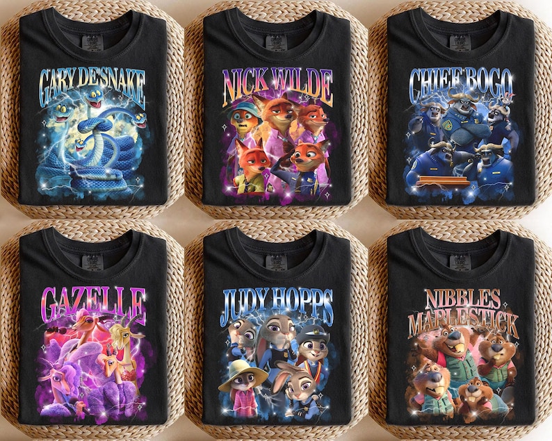 Puede incluir: Seis camisetas negras con gr&aacute;ficos coloridos que presentan personajes y texto de la pel&iacute;cula animada "Zootr&oacute;polis". Las camisetas muestran nombres como "Gary Desnake", "Nick Wilde" y "Chief Bogo" en fuentes estilizadas, con ilustraciones vibrantes.