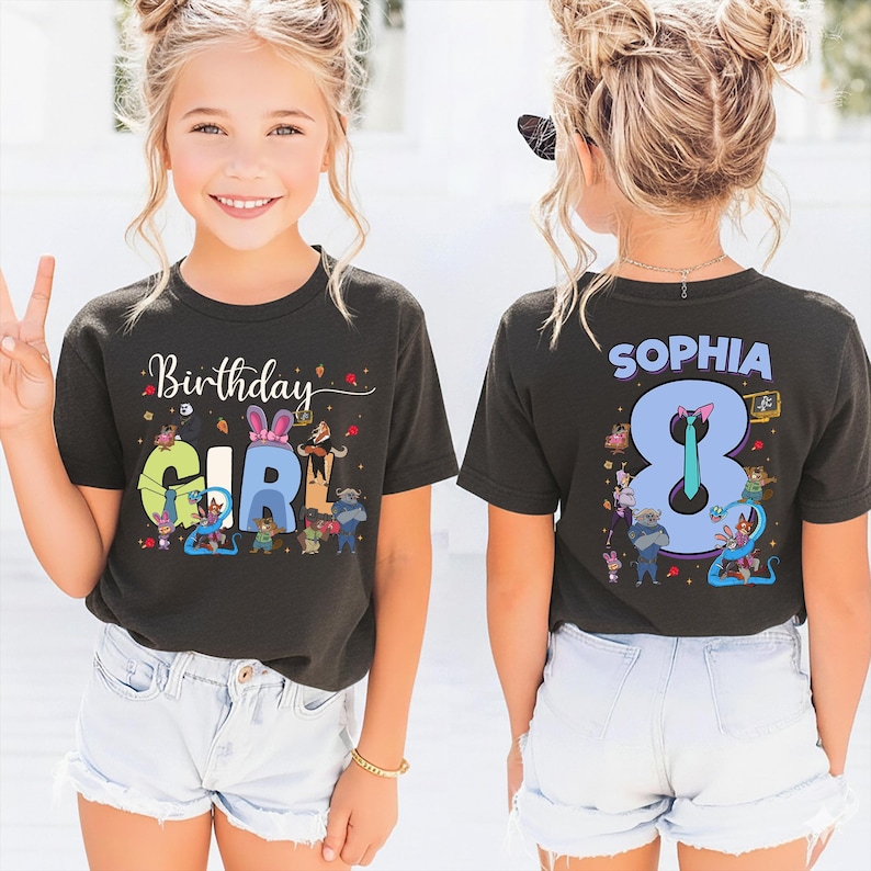 K&ouml;nnte beinhalten: Ein schwarzes T-Shirt mit den Worten "Birthday GIRL" in bunten Buchstaben und Zeichentrickfiguren. Auf der R&uuml;ckseite des Shirts steht der Name "SOPHIA" &uuml;ber einer gro&szlig;en "8" mit Zeichentrickfiguren. Das M&auml;dchen tr&auml;gt wei&szlig;e Shorts.