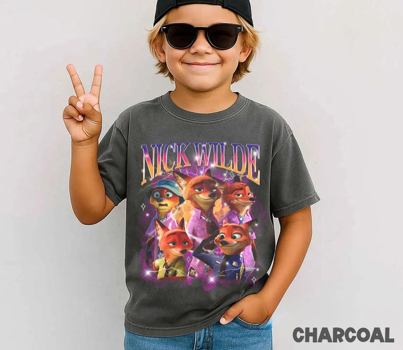 Puede incluir: Camiseta gris carb&oacute;n con un gr&aacute;fico de Nick Wilde de Zootopia. El dise&ntilde;o incluye el texto "NICK WILDE" en un estilo retro, con im&aacute;genes del personaje. La camiseta es de estilo vintage.