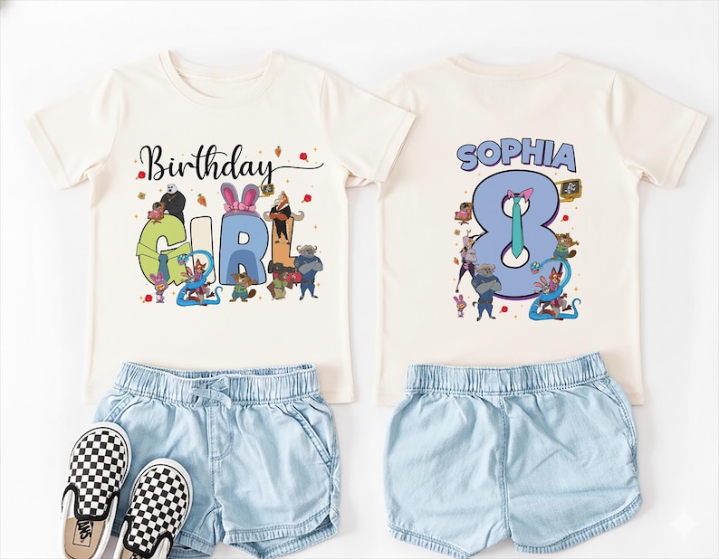 K&ouml;nnte beinhalten: Ein cremefarbenes Geburtstags-T-Shirt mit den Worten "Birthday GIRL" in bunten Buchstaben und Zeichentrickfiguren. Auf der R&uuml;ckseite des Shirts steht der Name "SOPHIA" &uuml;ber der Zahl "8". Kombiniert mit hellblauen Jeansshorts und karierten Slip-On-Schuhen.