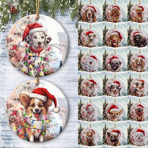 Op de afbeelding: Ronde kerstversieringen met verschillende hondenrassen die kerstmutsen en lichtjes dragen. De honden zijn onder andere een Dalmatische hond en een Corgi. De ornamenten zijn wit en hebben een touwtje om op te hangen.