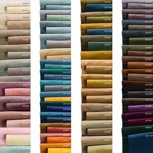 Op de afbeelding: Een kleurenkaart met een breed scala aan stofstalen in verschillende tinten. De stalen zijn gerangschikt in verticale kolommen en tonen een spectrum van kleuren, van gedempte neutralen tot levendige tinten. Elke staal is voorzien van een unieke code.