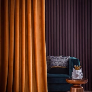 May include: An opulent interior with a mustard velvet curtain, a teal sofa with patterned cushions, and a small copper side table. A white lion head statue with a gold crown is on the table. The background features dark wood paneling.