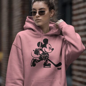 Ice hockey-themed design featuring Mickey Mouse with hockey player silhouettes and clipart. Includes SVG and PNG files, perfect for crafting, t-shirts, and sports-themed decorations. Ideal for Disney fans creating fun, hockey-inspired projects.