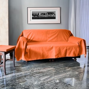 Op de afbeelding: Een feloranje sofadeken gedrapeerd over een bank. De deken is gemaakt van een zachte, pluche stof en is perfect om een vleugje kleur toe te voegen aan elke woonkamer.
