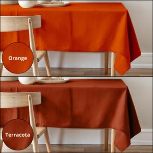 Puede incluir: Dos manteles, uno naranja y otro terracota, se muestran drapeados sobre una mesa de madera con una silla de madera. Los manteles est&aacute;n hechos de un tejido similar al lino.