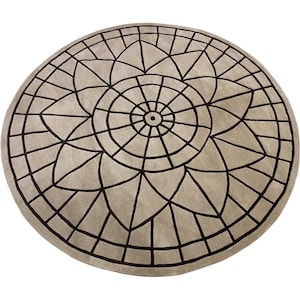 May include: A round, beige rug with a black geometric design. The design features a large, central flower with a smaller circle in the center. The rug has a subtle, textured surface.