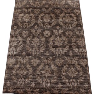 May include: A rectangular brown rug with a floral pattern in shades of beige and brown. The rug has a fringe on the short ends. The design features repeating floral motifs across the surface, creating a classic and elegant look. The rug is suitable for living rooms and bedrooms.