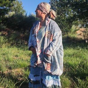 Könnte beinhalten: Eine langärmelige Patchwork-Kimono-Jacke aus einer Mischung aus blauem Karostoff und rotem Blumenmuster, getragen über einem hellgrünen Oberteil und einem gestuften blauen Jeansrock mit weißen und dunklen Stoffrüschen am Saum.