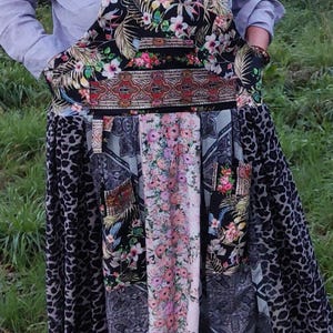 May include: A long black and white floral print overall dress with a leopard print panel and a floral print panel. The dress has a gathered skirt and a wide waistband.