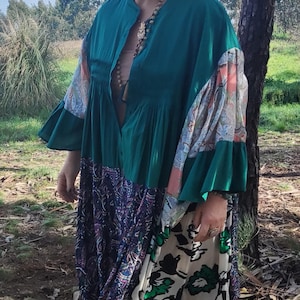 Pode incluir: Um vestido longo estampado em verde, azul e branco com botões na frente e mangas compridas. O vestido tem uma saia franzida e um caimento solto.