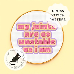 May include: A cross-stitch pattern in a gold hoop features the phrase "my joints are as unstable as I am" in pink and yellow letters. A black cat logo is in the lower left corner, and the words "Cross Stitch Pattern" are in the upper right.