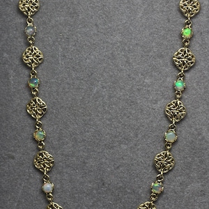 May include: A gold necklace with a Celtic knot design and opal stones.