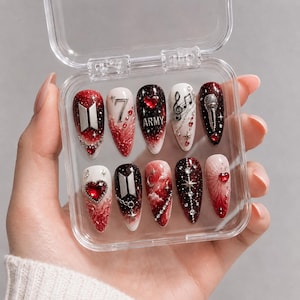 Pode incluir: Um conjunto de dez unhas postiças em formato amendoado dentro de um estojo de plástico transparente. Os designs apresentam uma paleta de cores vermelha, preta e branca com detalhes metálicos, incluindo o logo BTS, o número 7, a palavra ARMY, notas musicais e um microfone.
