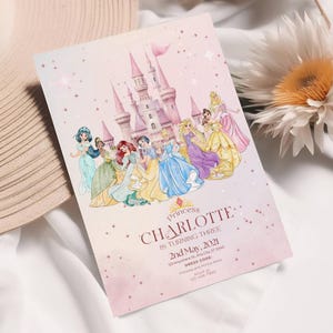 K&ouml;nnte beinhalten: Eine rosa Einladungskarte mit einer Aquarellillustration eines Schlosses und Prinzessinnen. Der Text lautet "Princess Charlotte is turning three" mit Veranstaltungsdetails. Die Karte hat eine weiche, vertr&auml;umte &Auml;sthetik.