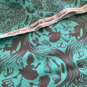 Op de afbeelding: Een turquoise stof met een donkerbruin herhalend patroon van silhouetten, waaronder bomen, boeken, stoelen, klokken en vogelkooien. De witte zelfkant toont de tekst "FreeSpirit presents Curiouser & Curiouser by Tula Pink".