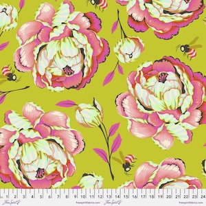 Op de afbeelding: Een stofprint met grote roze en witte pioenen op een chartreuse groene achtergrond, afgewisseld met kleine vliegende bijen. Een witte liniaal onderaan toont afmetingen in centimeters, van 1 tot 24 cm, met de tekst freespiritfabrics.com.
