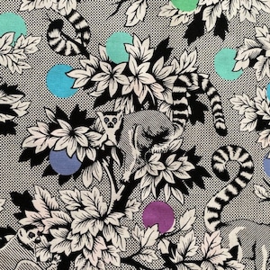 Puede incluir: Una tela con un estampado floral y de lémures en blanco y negro. El diseño incluye flores estilizadas, lémures y colas a rayas, con lunares de colores en verde azulado, morado y verde. El fondo tiene una textura punteada.
