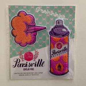 May include: A set of two chenille patches. One patch is a pink and orange cloud-like shape. The other is a pink and orange Parisville Hairspray can. The text "Parisville" and "Limited Edition Hairspray Can & Spray" are visible.