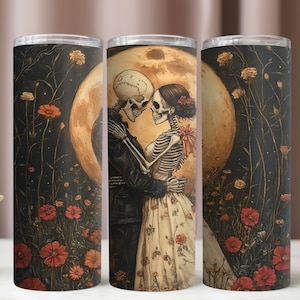 May include: Two skeletons dressed in formal attire are embracing under a full moon. The skeletons are surrounded by a field of flowers. The image is printed on a black and white tumbler.