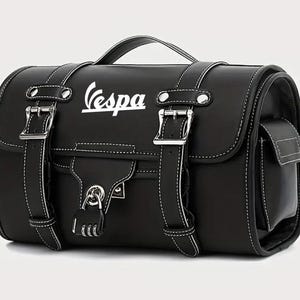 Könnte beinhalten: Schwarze Vespa-Roller-Tasche aus Leder mit weißen Nähten, einem oberen Griff und silbernen Schnallen. Die Tasche trägt das Vespa-Logo in Weiß und einen Zahlenschlossverschluss. Eine kleine Seitentasche ist sichtbar.