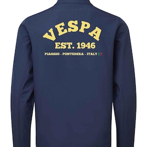Könnte beinhalten: Marineblaue Jacke mit Reißverschluss und dem gelben Wort "VESPA" auf dem Rücken, zusammen mit "EST. 1946" und dem Text "PIAGGIO - PONTEDERA - ITALY" darunter. Die Jacke hat einen Stehkragen.