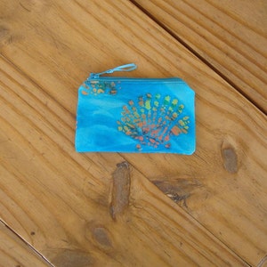 May include: A small blue fabric coin purse with a zipper closure. The purse has a colorful floral pattern.