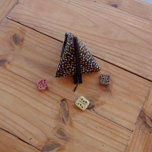 May include: A black triangular zippered pouch with a white and orange bone pattern. The pouch is on a wooden surface with three dog treats.