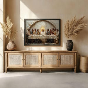 May include: A framed artwork depicting the Last Supper scene, with figures gathered around a table. The artwork is displayed above a light wood cabinet with woven door panels. Decorative vases with dried plants flank the artwork.