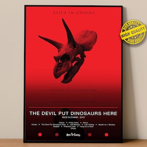 May include: A framed poster with a red background features a dinosaur skull illustration. The text "ALICE IN CHAINS" and "THE DEVIL PUT DINOSAURS HERE" are displayed. The poster includes a list of song titles and the year 2013.